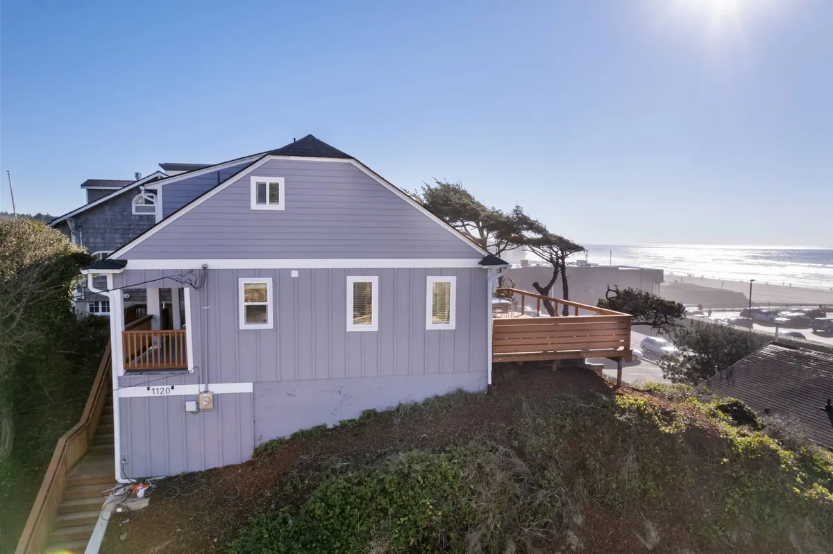 This image shows the exterior of the house with a spacious deck and clear views of the ocean beyond. The scene captures the peaceful ambiance, with outdoor furniture ideal for relaxing or socializing while enjoying the sea breeze and panoramic views.